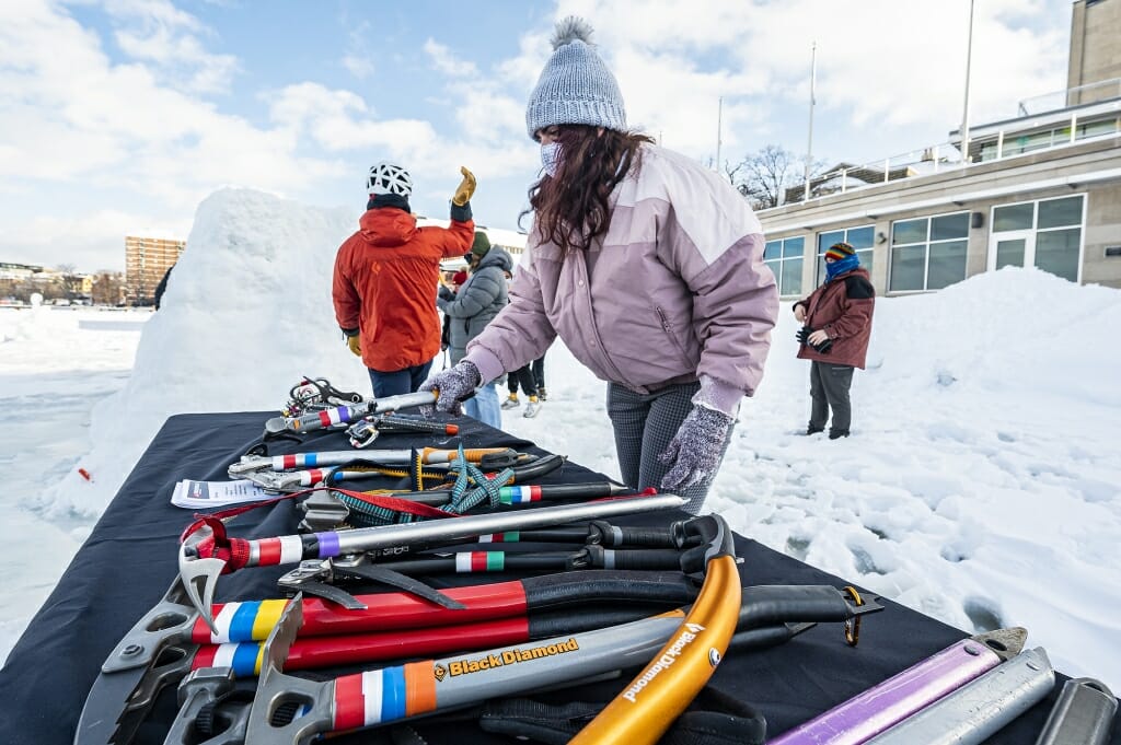 A participant selects an ice axe from a table of climbing equipment.