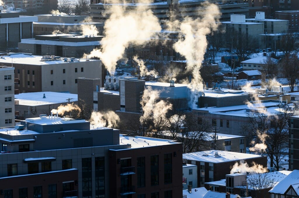 Steam rises from the chimneys and ventilation systems of and snow-covered buildings in the southeast area of campus.