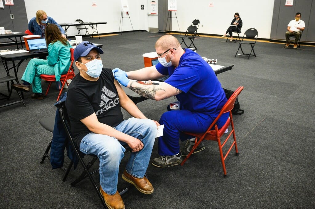 Photo of UHS registered nurse Dan Hunter vaccinating Ricardo Portillo.