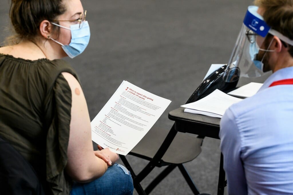 Photo of Amber Brunes, who works with people with disabilities at a Madison-area independent living center, listening to follow up instructions after being vaccinated.