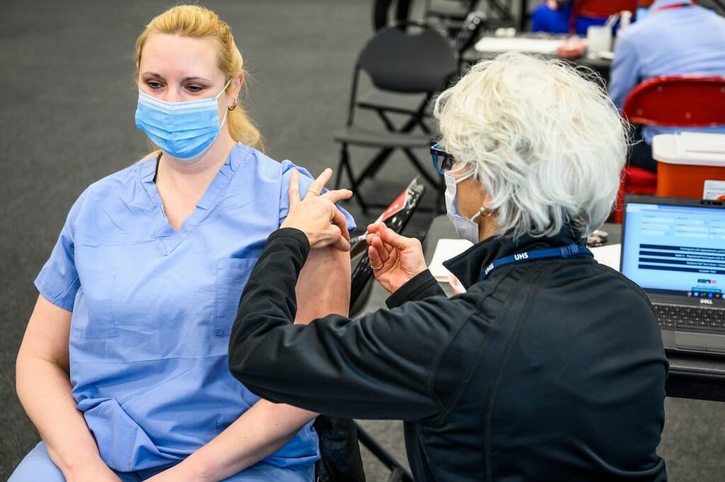 Person administering vaccination to patient