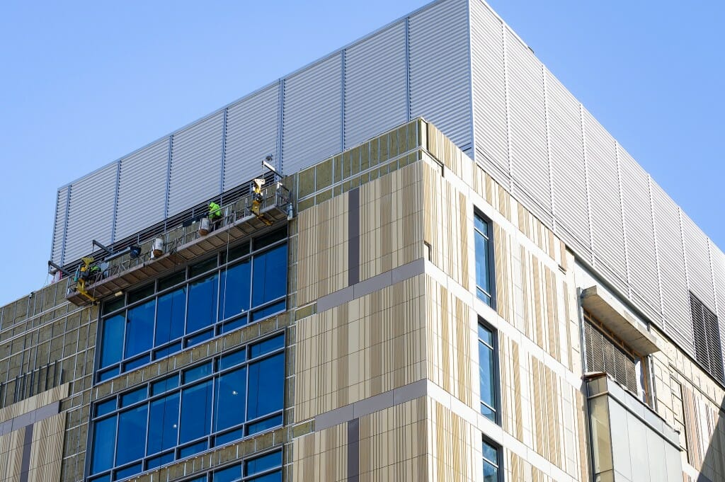 Construction workers work on the exterior facade of an addition to the Chemistry Building.