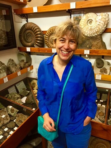 Pupa Gilbert standing next to shelves containing shells