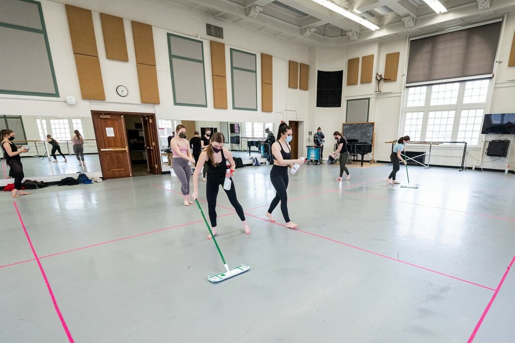 Students clean and sanitize their rehearsal sections  at the end of Dance 112.