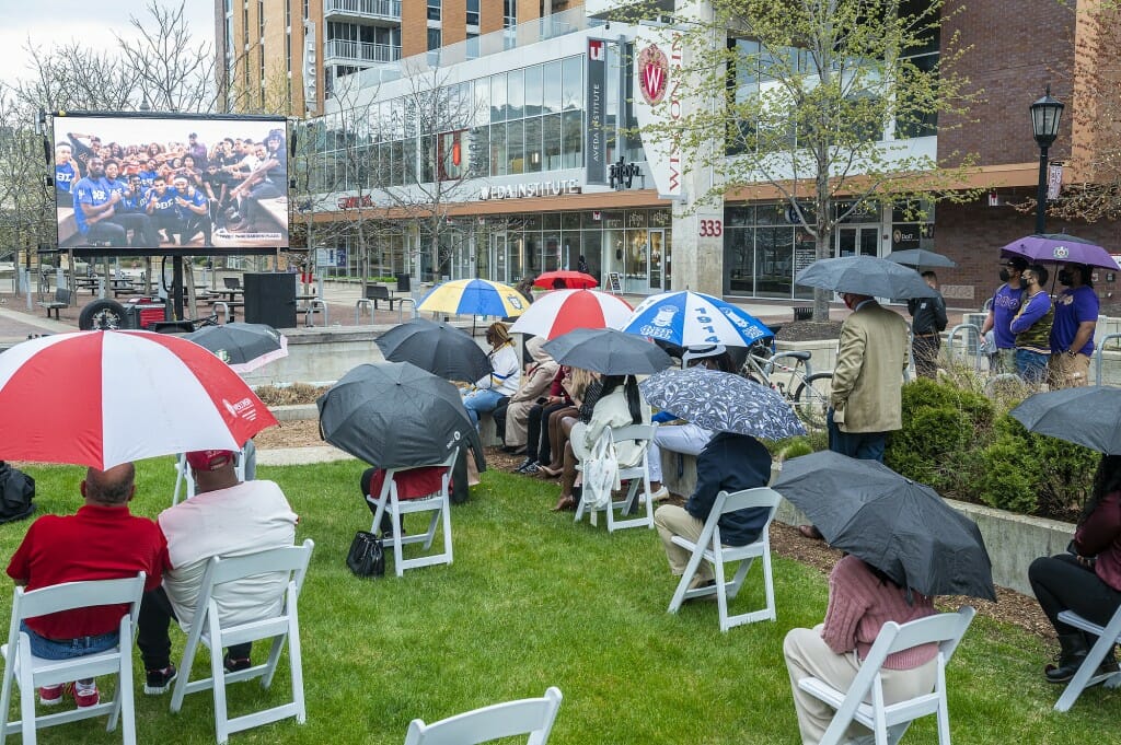 Attendees watch a video presentation on a large outdoor screen during the dedication ceremony.