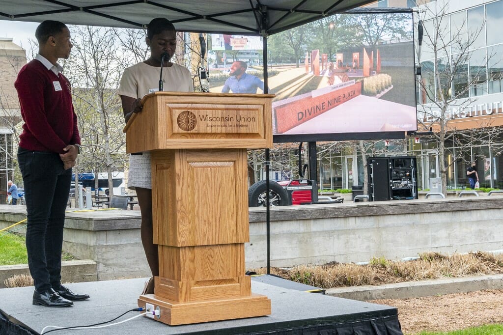 Undergraduates Nyla Mathis (right) and Israel Oby (left) unveil design plans on a large outdoor screen.