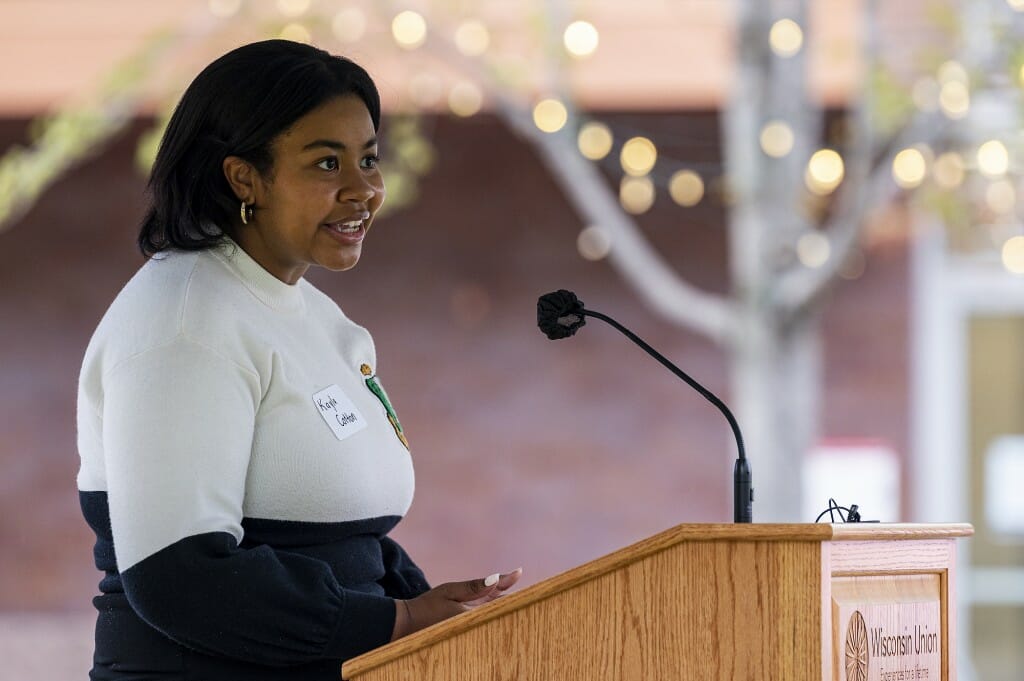 Undergraduate Kayla Cotton speaks during the ceremony about the importance of recognizing the Divine Nine. The site, currently a grassy area with park benches, is across East Campus Mall from the Walgreens on West Johnson Street.