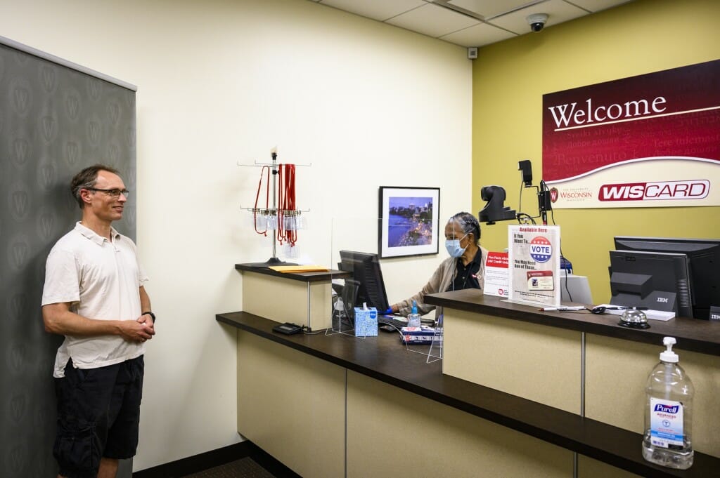 Man posing in front of screen and Almaz behind counter