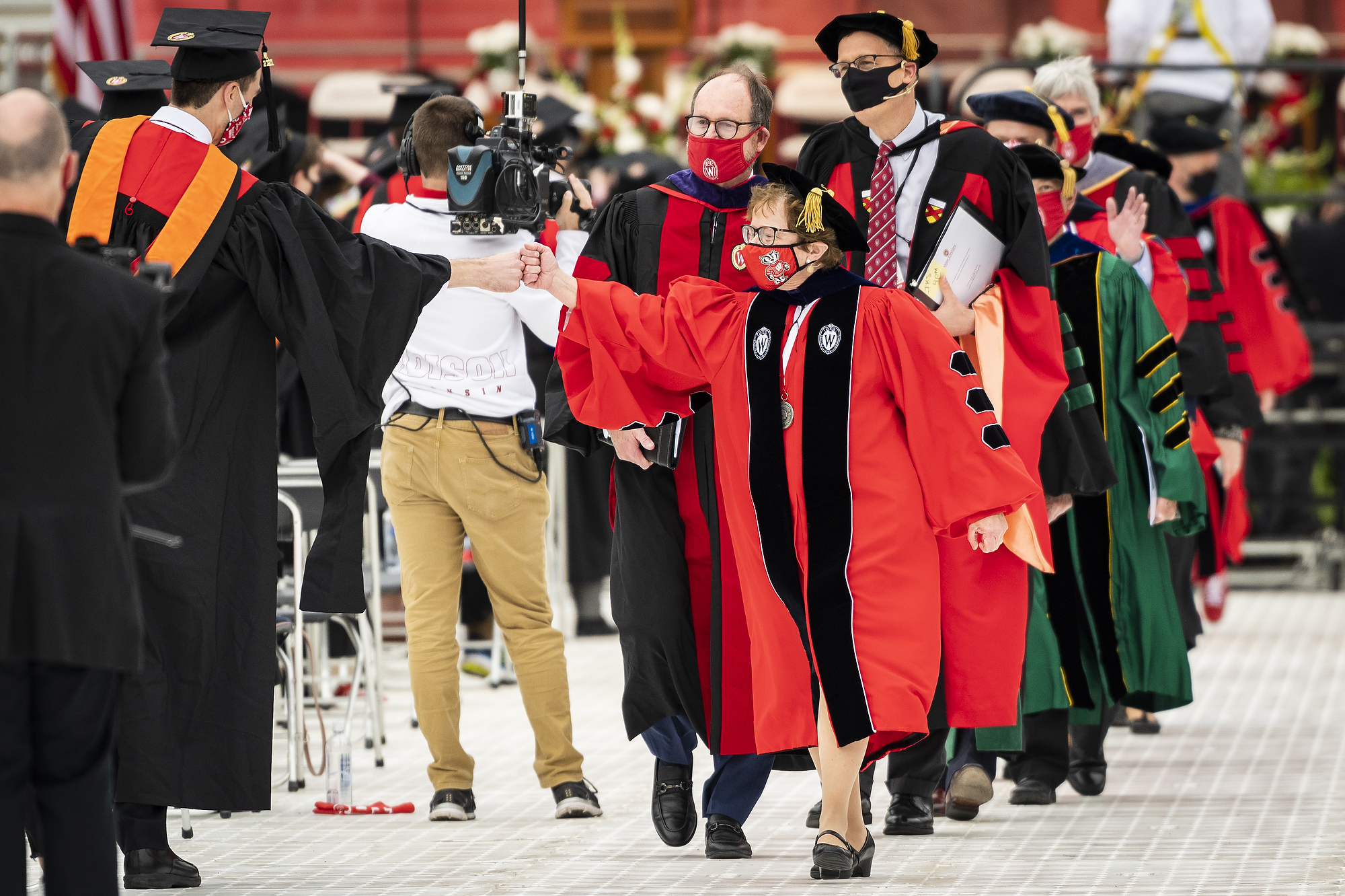 Photo of Chancellor Blank fist bumping a graduate as she leads the commencement procession out of the stadium.