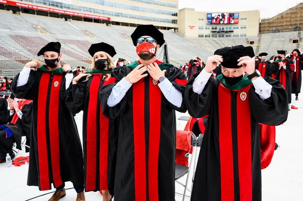 Photo of four graduates adjusting their green doctor of medicine hoods.