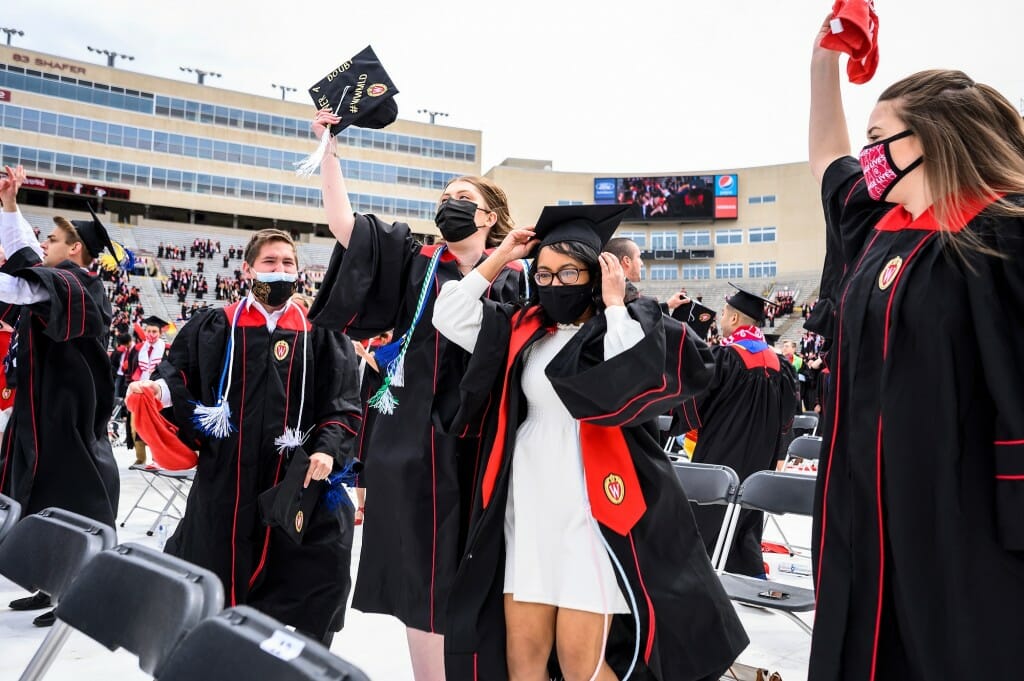 Photo of graduates jumping and tossing their mortarboards