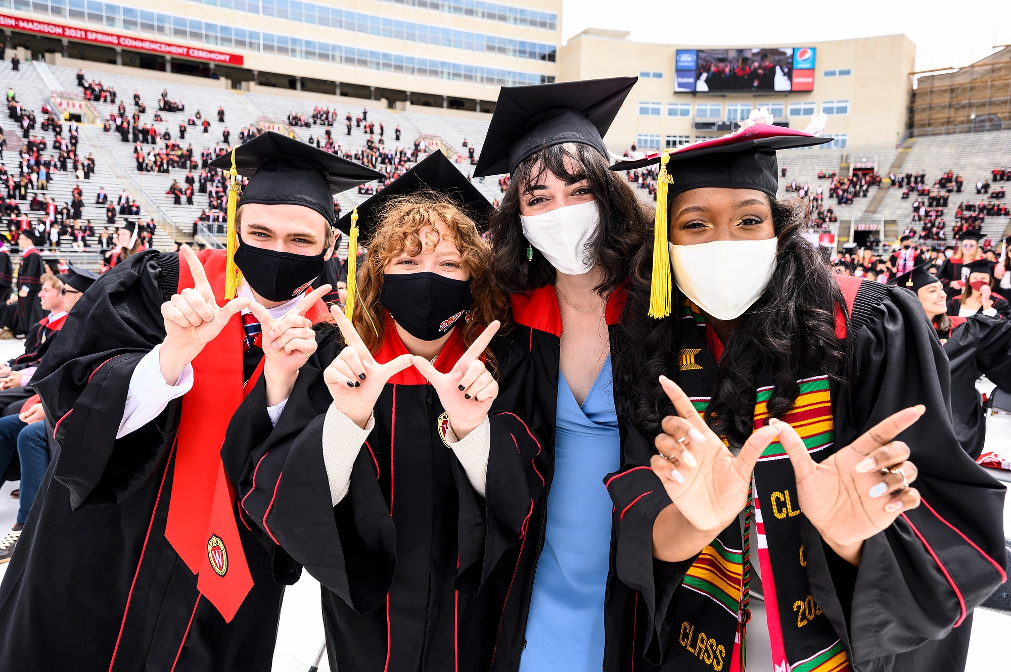 Four graduates flash the "W" with their hands.