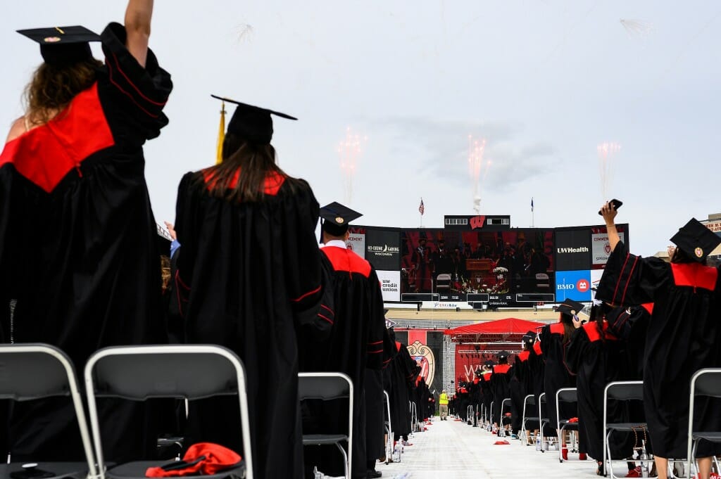 Graduates cheer as pyrotechnics launch from the scoreboard