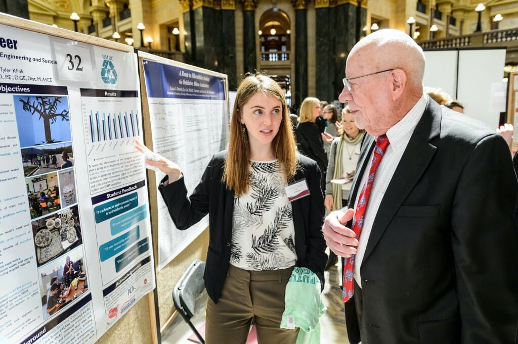 Student pointing to poster as Risser listens