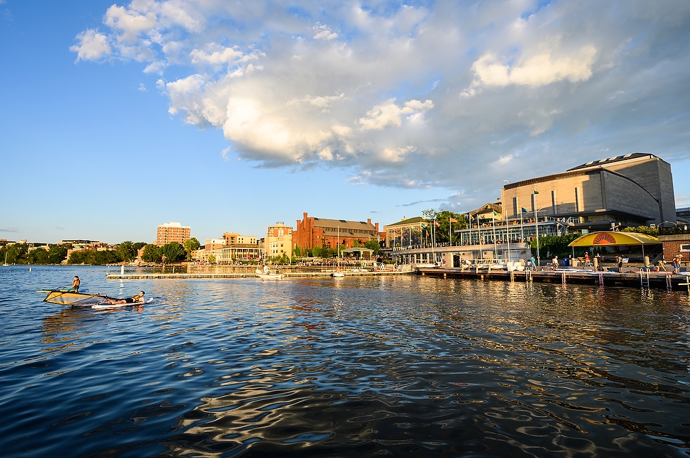 A blue sky with a few clouds is reflected in Lake Mendota with the Terrace in the background.