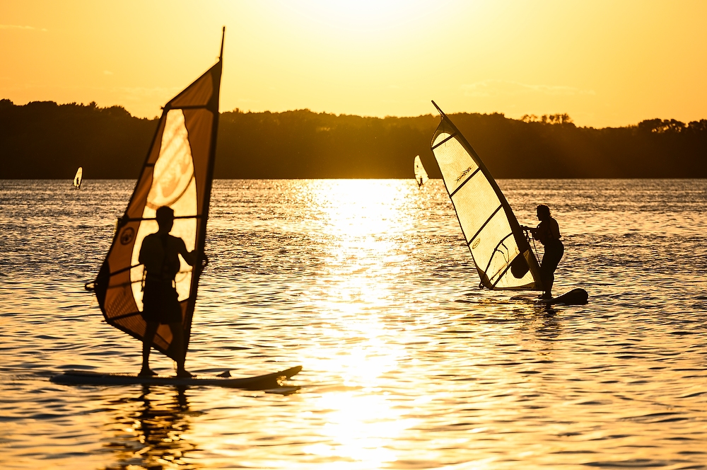 Two wind surfers on the dappled surface of the lake.