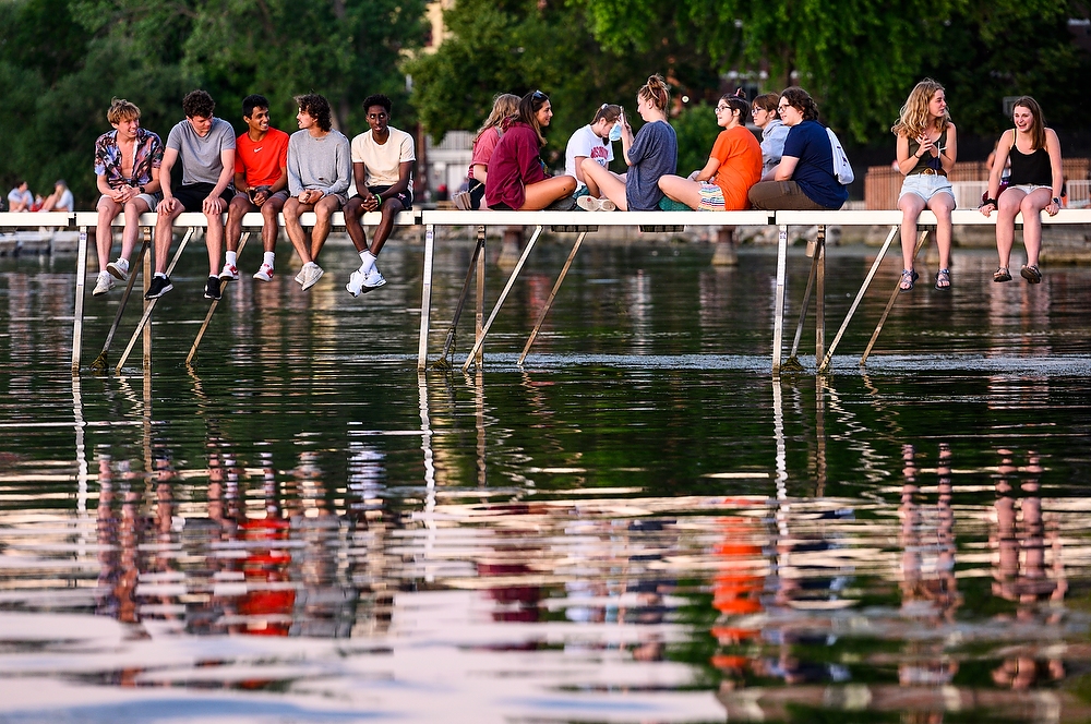 Students sit on a pier, talking and laughing.