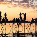 People are silhoutted by the setting sun as they sit on a pier in Lake Mendota.