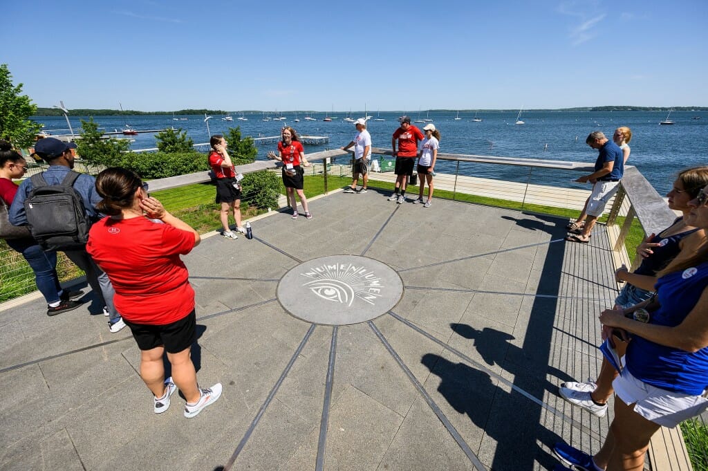 Group standing in circle around Numen Lumen symbol in pavement