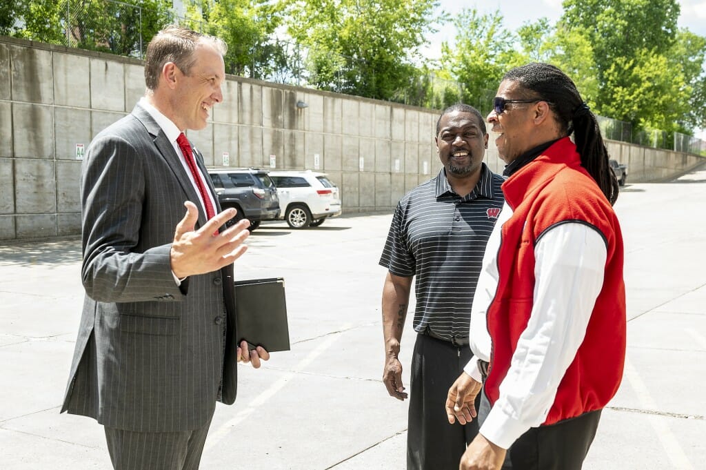 McIntosh (left) speaks with former football teammates Ron Dayne (center) and Cecil Martin (right) prior to a press conference.