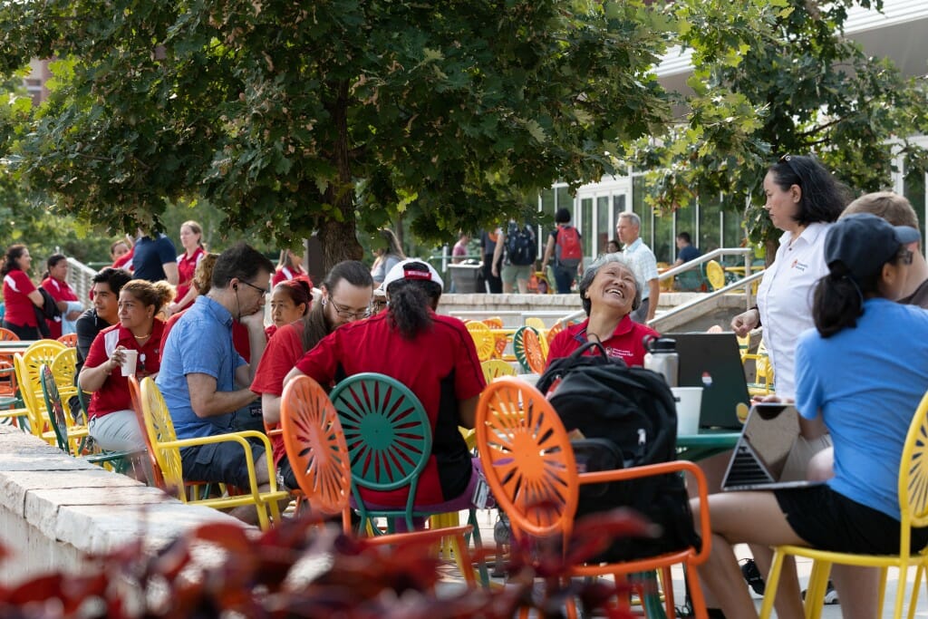 People laugh and joke with each other at a table on the terrace.