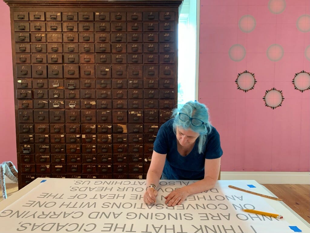 Angus leaning over a table working on lettering