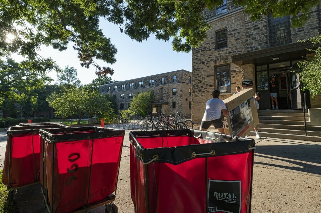 Everyone teams up to move a futon sofa into Showerman House in Kronshage Residence Hall.