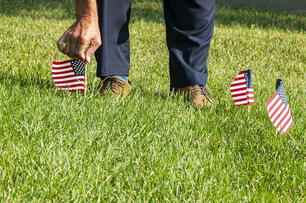 Mick Miyamoto, special projects coordinator for Student Affairs, places an American flag on Bascom Hill.