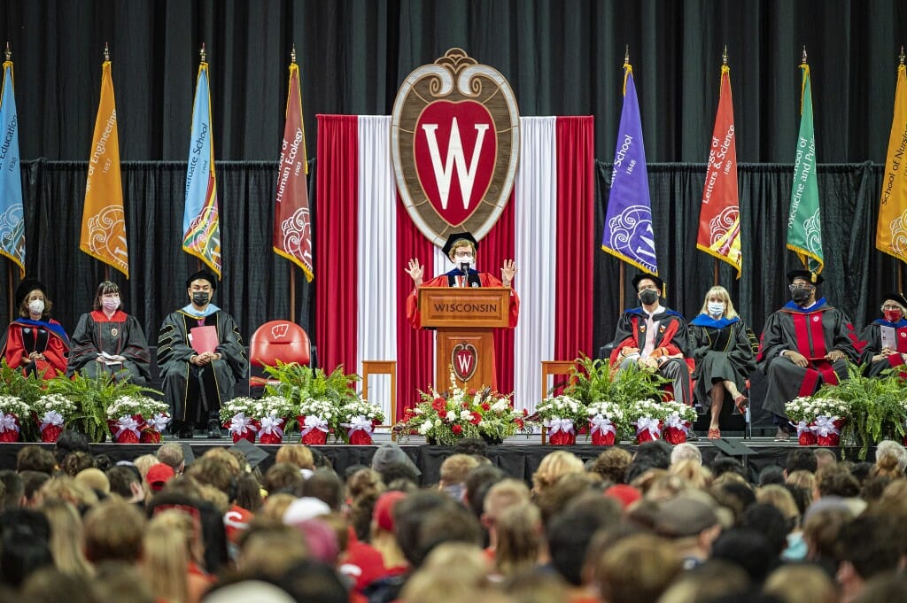 Blank speaking at podium under W crest