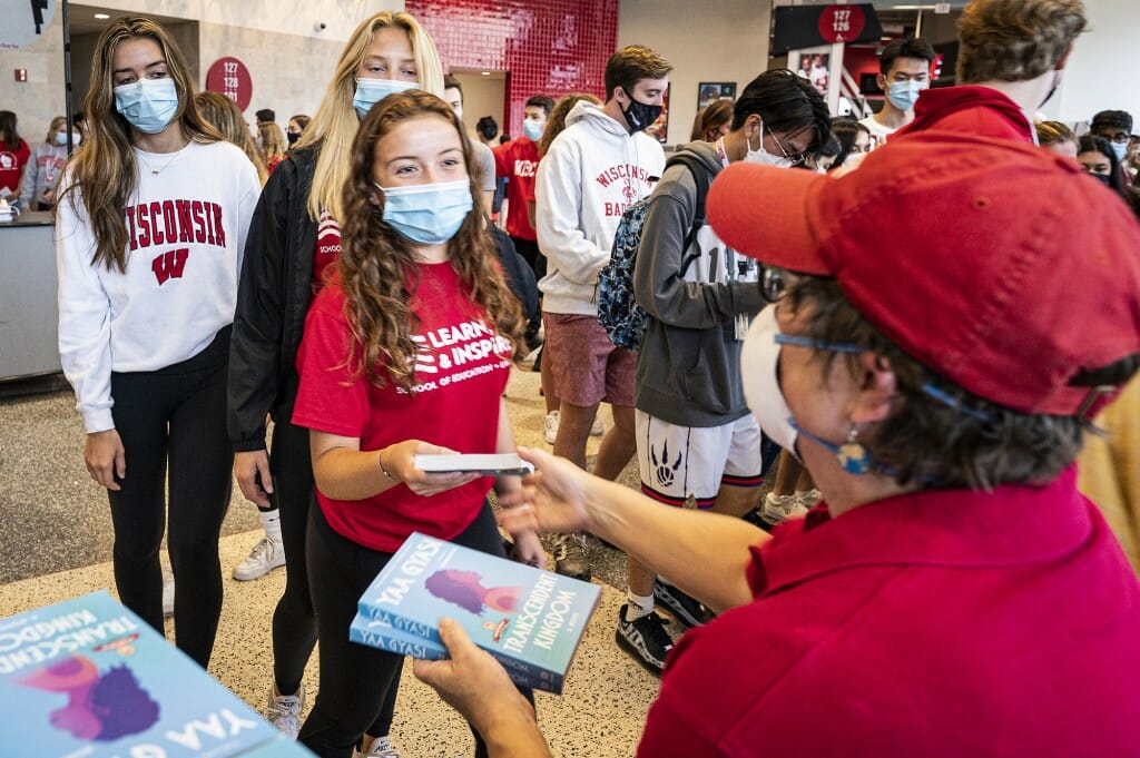 Person handing a book to a student