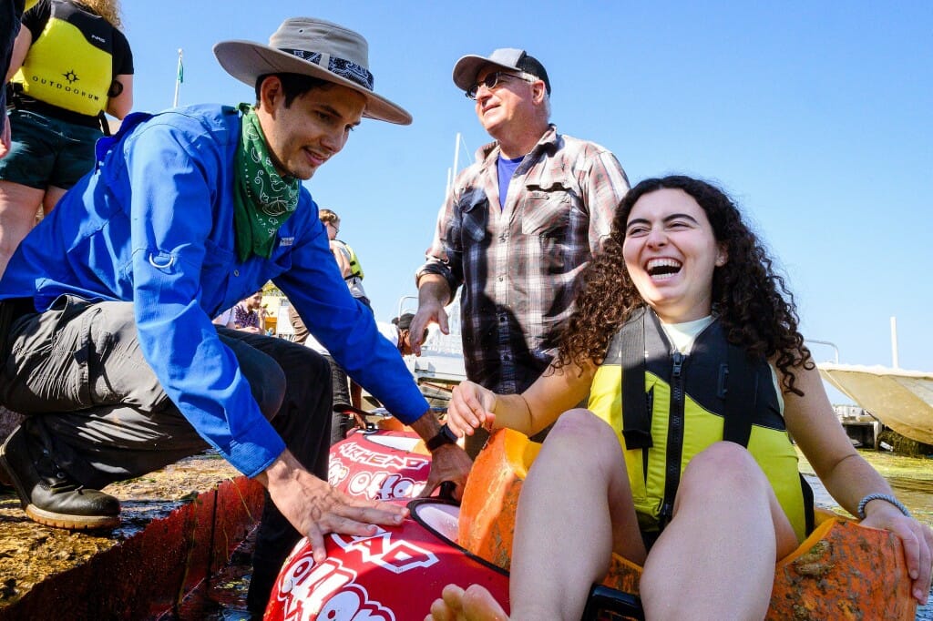 People helping child into pumpkin