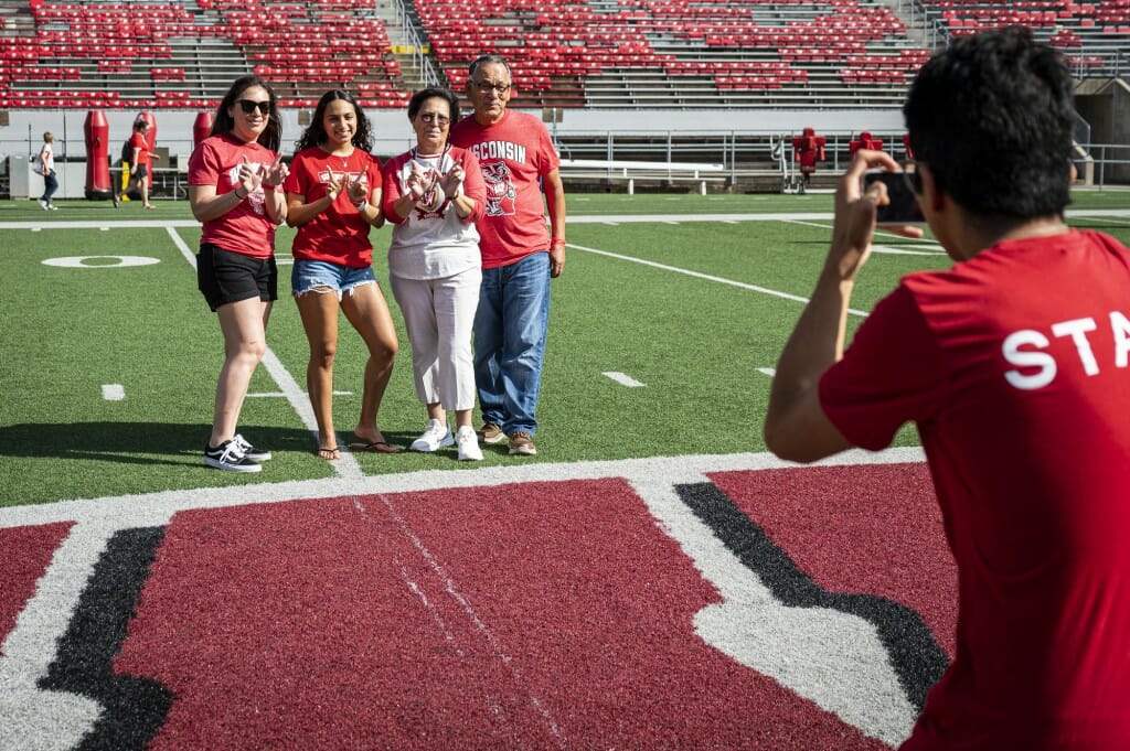 Kaila Land, along with her mother and grandparents, pose for a photo on the Motion W on the 50-yard line of the field at Camp Randall Stadium.