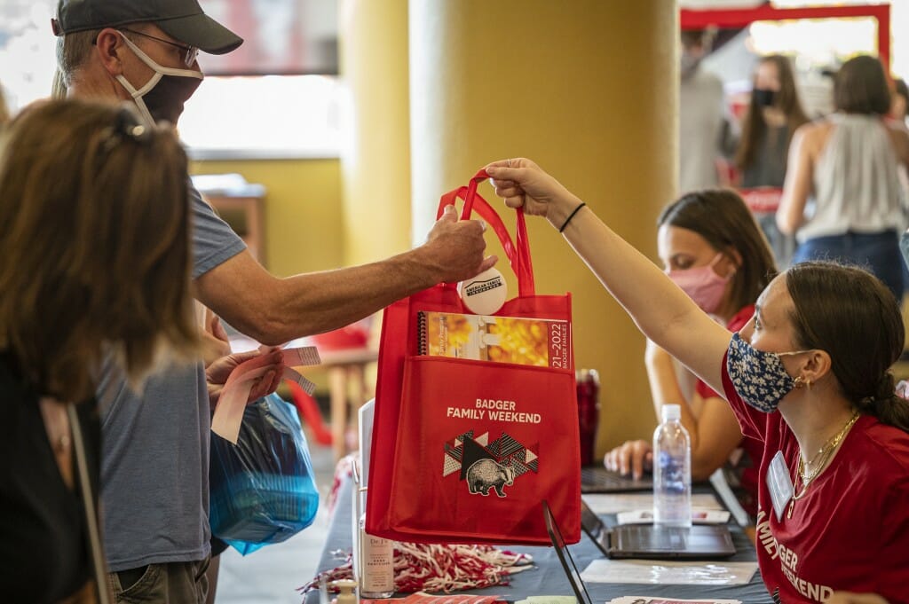 Staff members hand out bags filled with welcome gifts as families check in for Family Weekend at Union South.