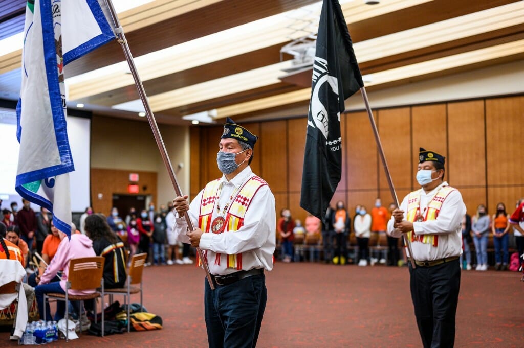 Military veterans Marlon and Marcus WhiteEagle, both of H0-Chunk Nation, enter with color guard flags.