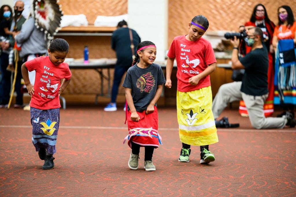 A group of young children dance.