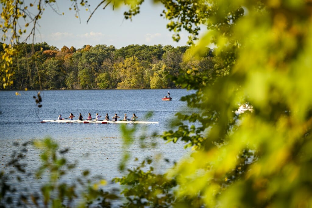 The women's crew team finds it's perfect weather for rowing practice on Lake Mendota — oar not, says the person in the fishing boat.