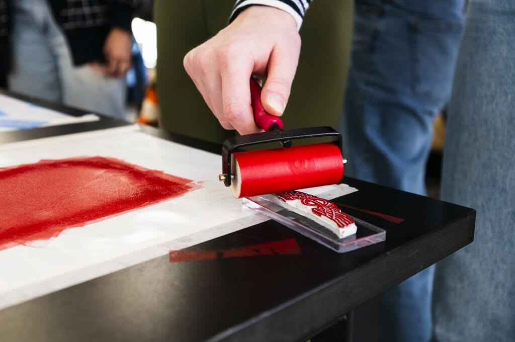 A participant rolls a brayer across a linoleum block.