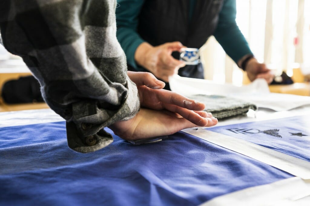 Freshman Eli Song presses an ink-covered linoleum block onto a handkerchief to transfer a pattern.