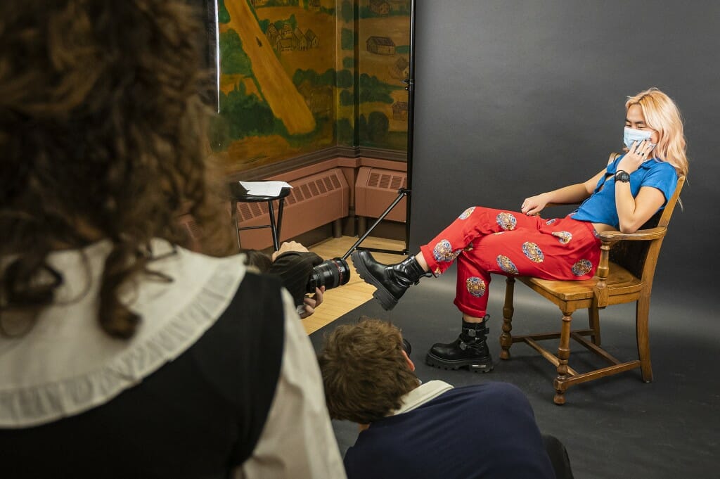 A woman stretches out in a chair as she's photographed.