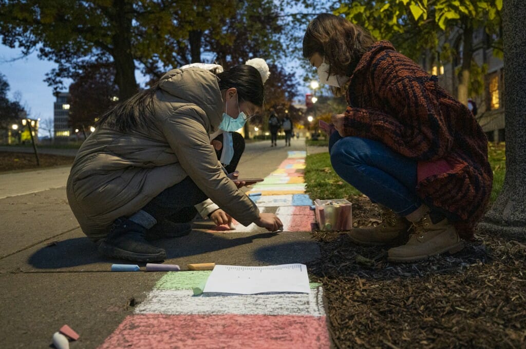 Honorary fellow Di Zhang (right) and visiting scholar Yuyang Jiang (left) draw international flags in chalk along the Bascom Hill sidewalk.