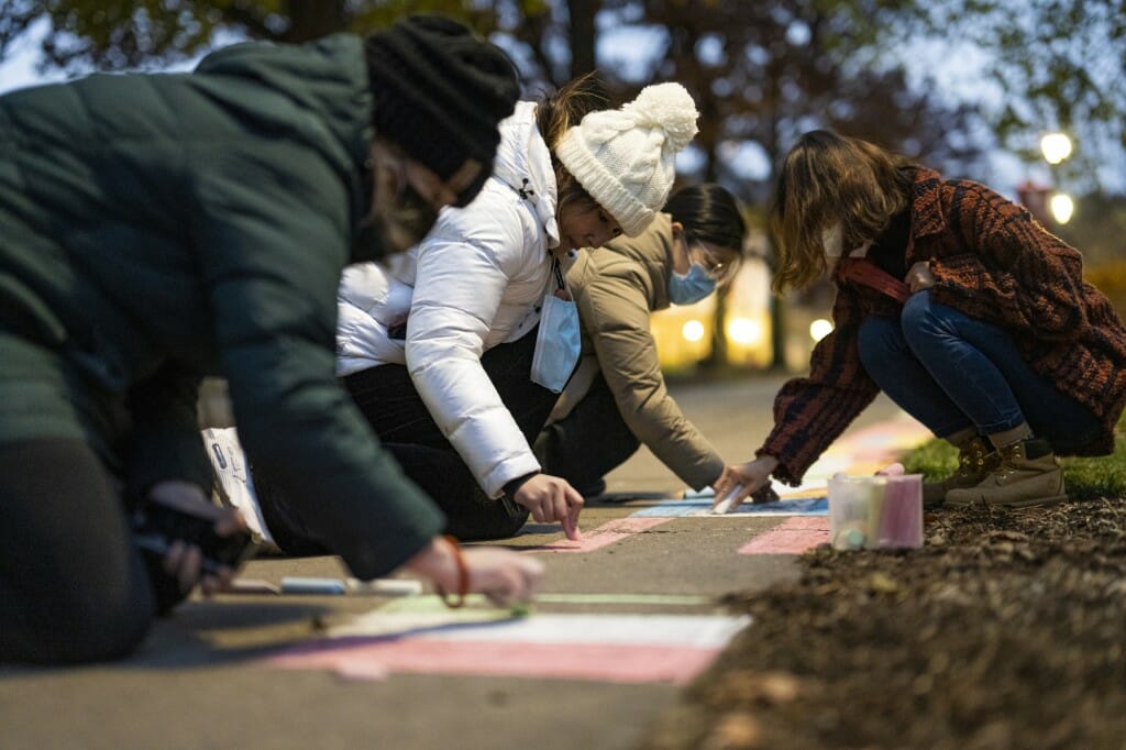 Undergraduate Intira Setavoraphan (center in white) draws an international flag in chalk. She is joined by Kate McCleary (left), associate director of the Global Engagement Office in the School of Education, visiting scholar Yuyang Jiang (back left) and honorary fellow Di Zhang (right).