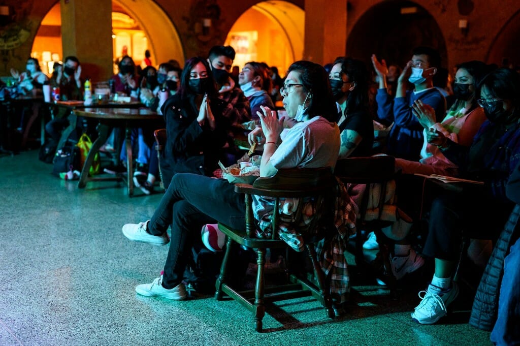 Audience members applaud a performer.