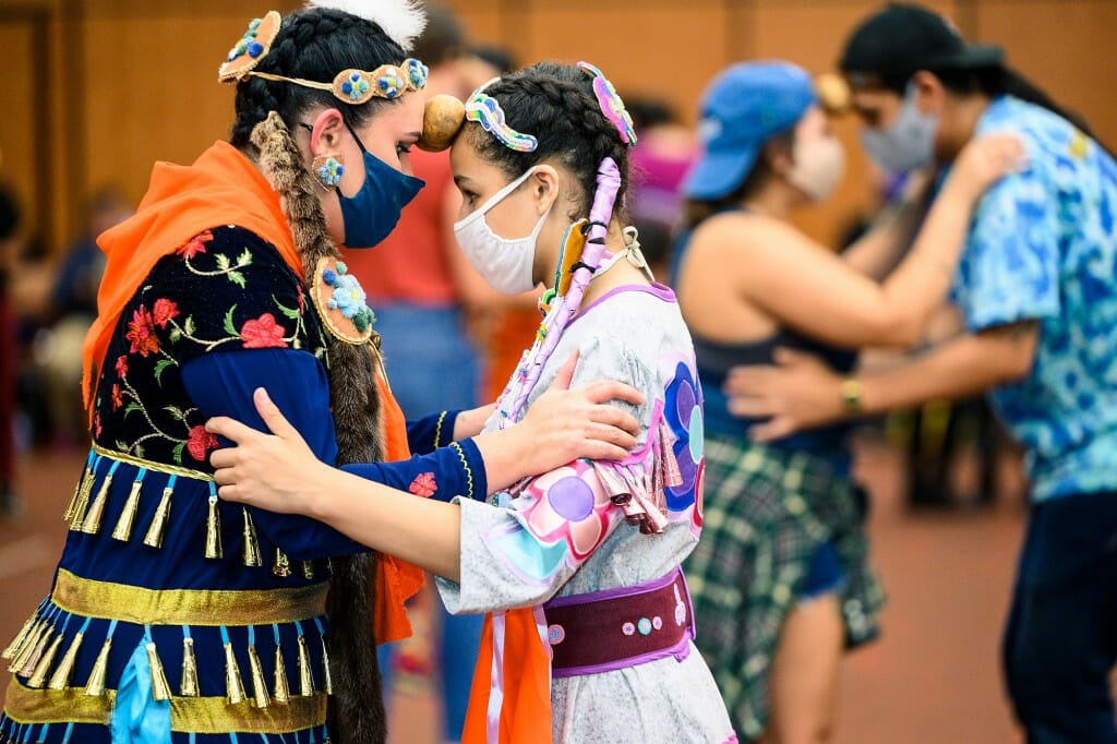 Two people dancing together with a potato held between their foreheads