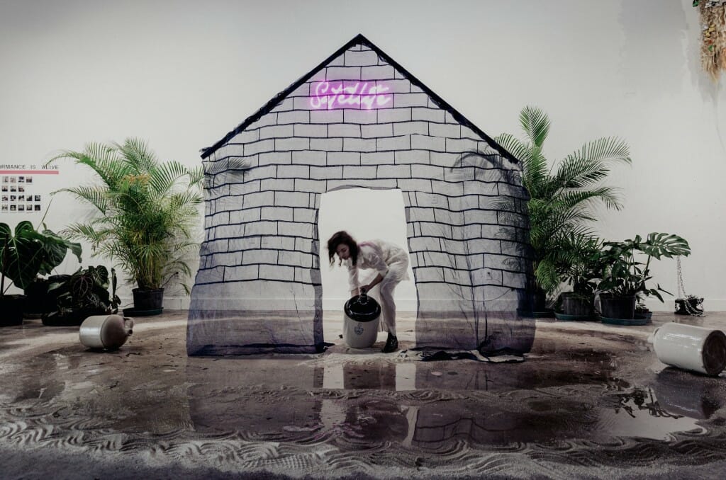 Photo: A woman scoops up buckets of water on a stage.