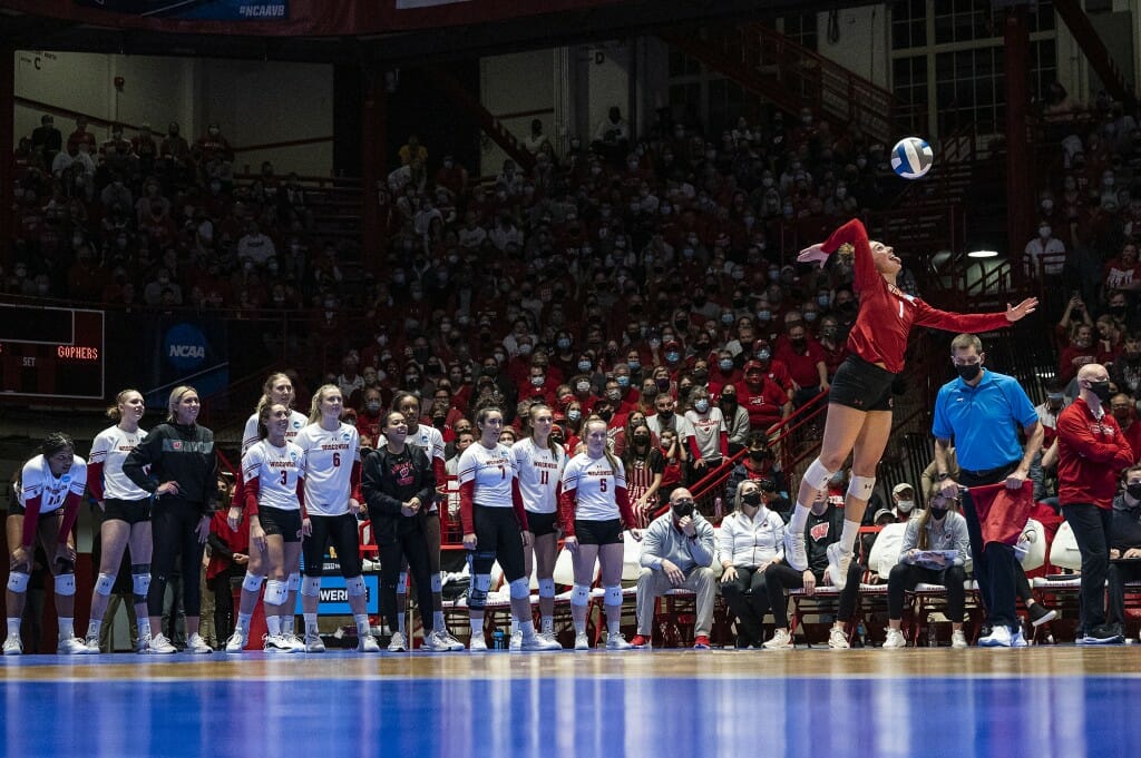 Lauren Barnes serves the ball as her teammates watch.