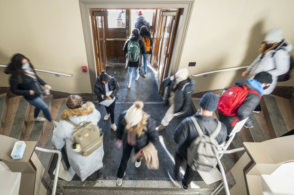 View from above looking down on students walking in and out of the front door.