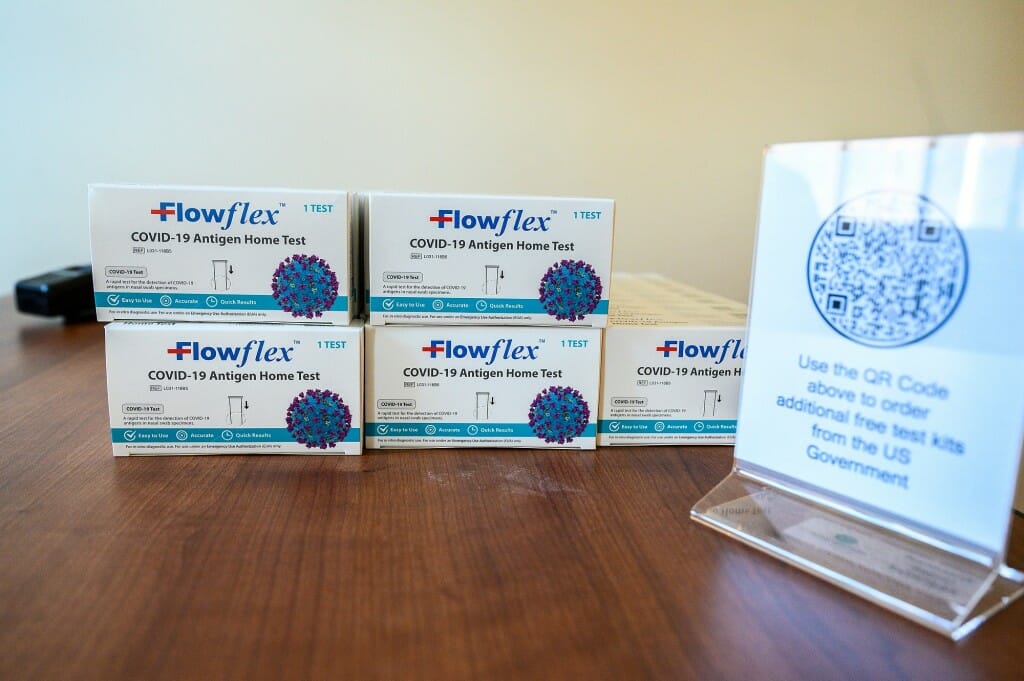 Boxes of antigen test kits are stacked on a table to be handed out