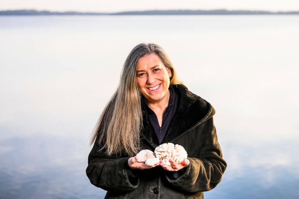 Gilbert standing in front of lake holding coral