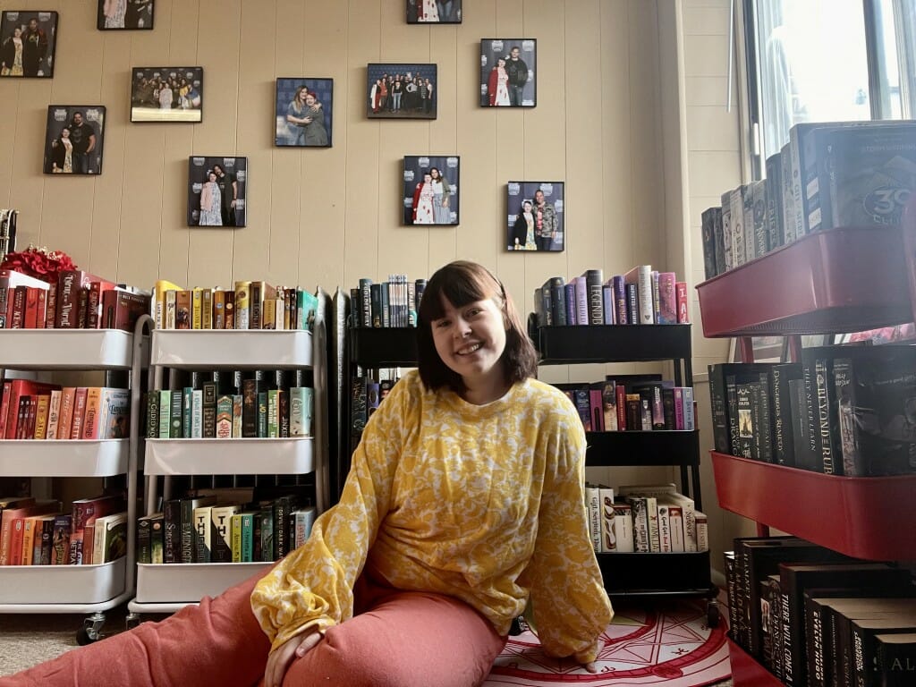 Photo: A woman sits in a room while surrounded by books.