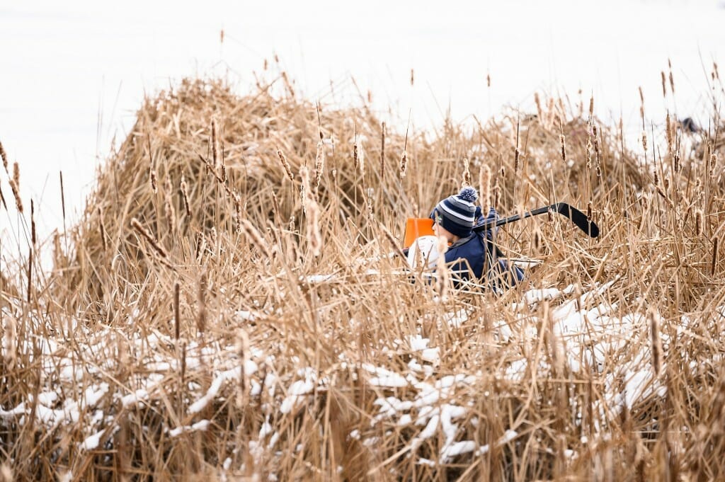 Photo: Two boys walk through thick reeds.